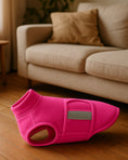 Load image into Gallery viewer, Bright pink fleece dog vest with reflective stripe displayed on wooden floor in front of a beige sofa.
